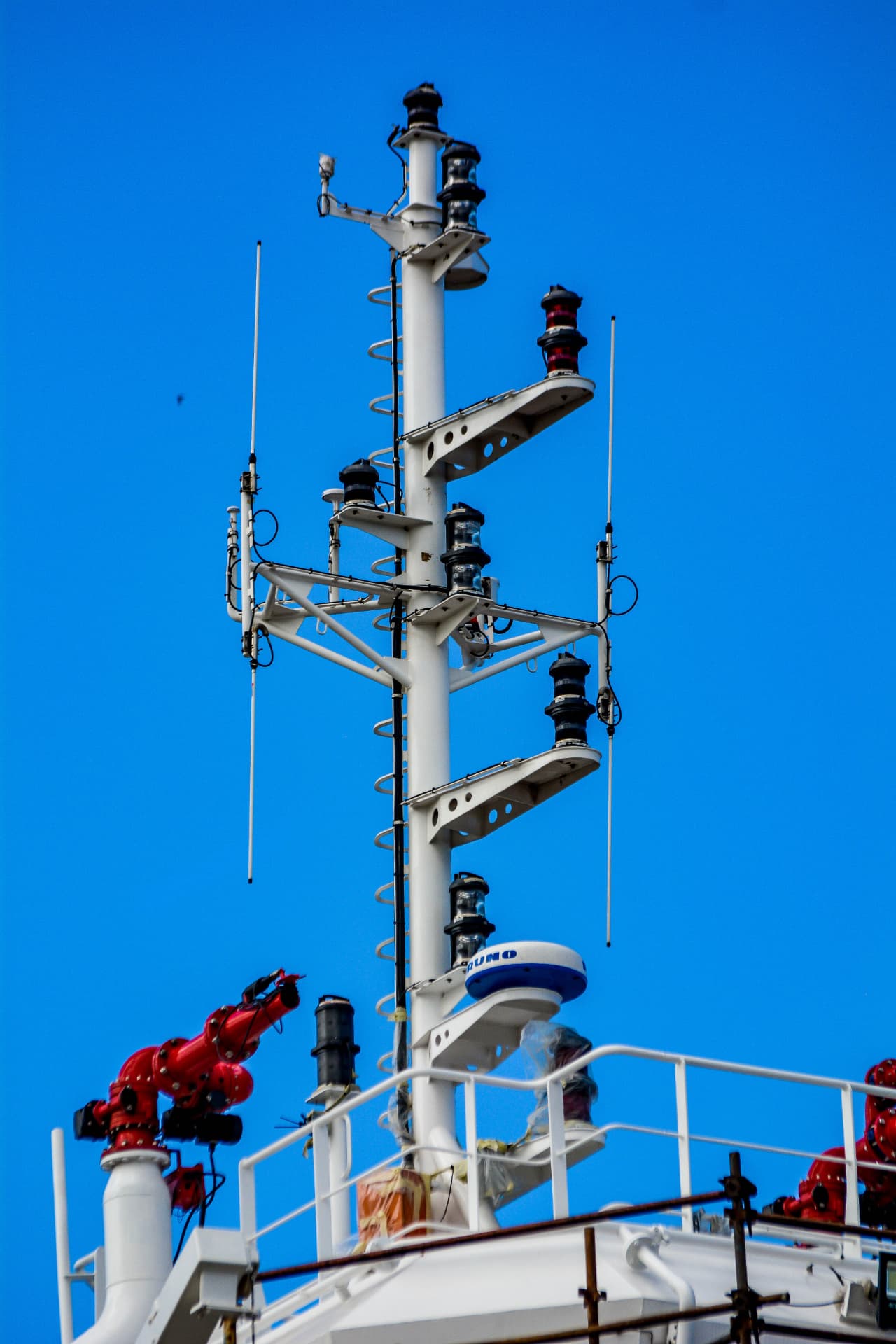 Fire monitors and mast on a marine vessel under blue sky